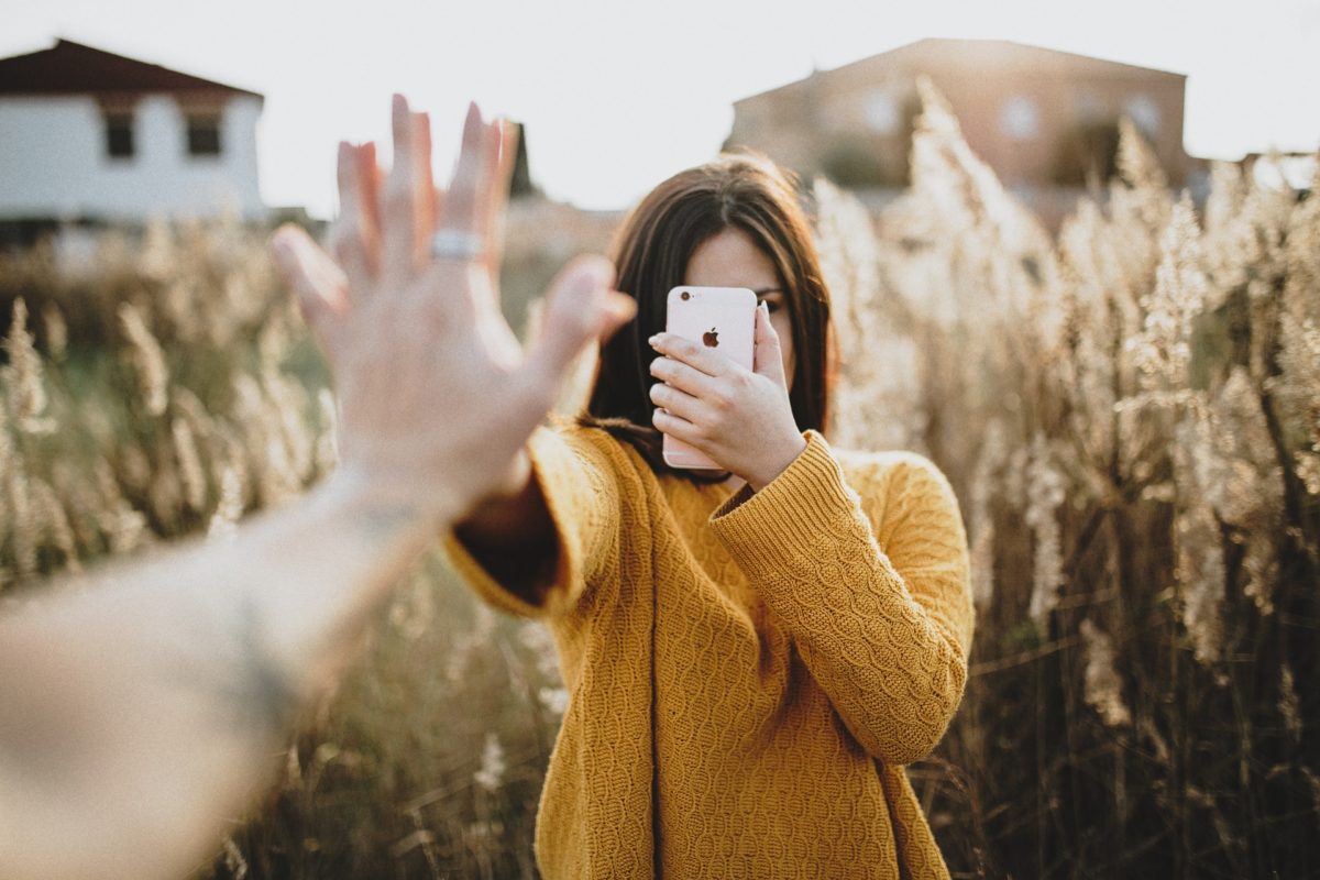 woman holding iphone while touching hands with the person holding the camera