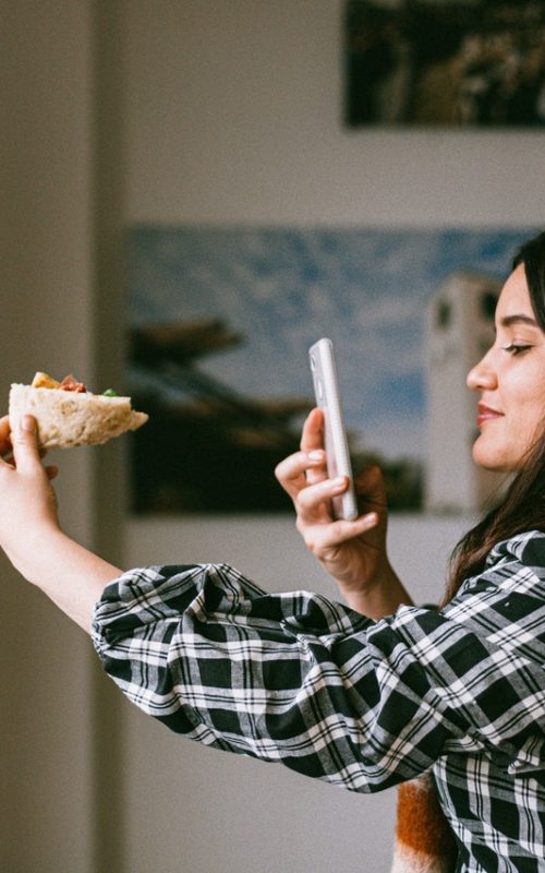 woman taking a photo of her pizza slice