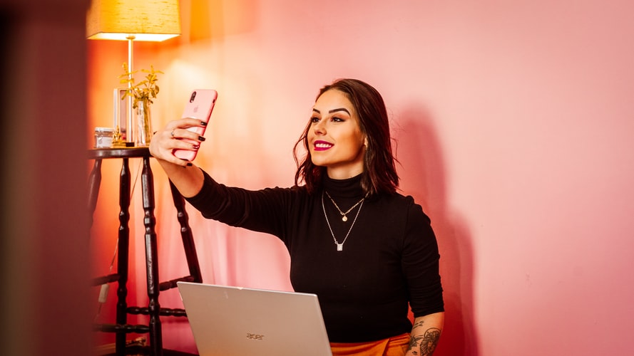 women taking selfie against pink wall